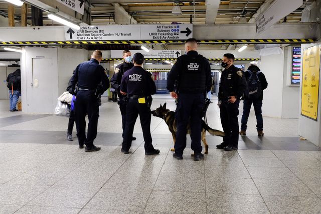 MTA police and NYPD stand guard at Penn Station. While the mayor and governor say train stations can no longer serve as a de facto shelter system, they continue to be used as one.